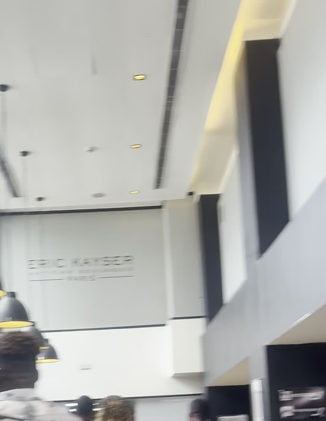 Pendant lamps running down the Ikoyi atrium beneath the Eric Kayser Artisan Boulanger wall